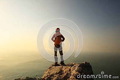 Hiker stand on the cliff edge at sunrise seaside Stock Photo