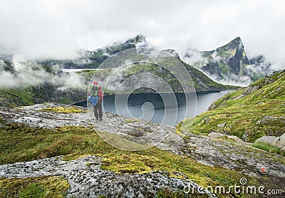 Hiker standing beside a lake in the Lofoten mountains on a foggy day Editorial Stock Photo
