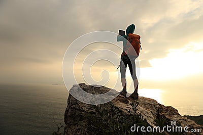 Hiker use digital tablet taking photo on seaside mountain peak rock Stock Photo