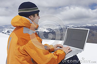 Hiker Using Laptop On Snowy Mountain Landscape Stock Photo