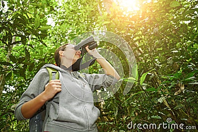 Hiker watching through binoculars wild birds in the jungle Stock Photo