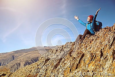 Hiker woman with backpack sitting on rock of a mountain and enjoying sunrise Stock Photo