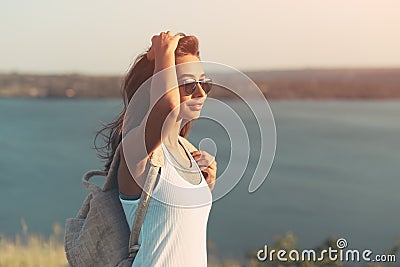 Hiker woman with backpack walking outdoors in summer at sunset Stock Photo