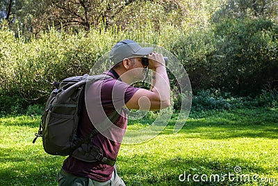 Man explorer in the forest, scanning the horizon with binoculars Stock Photo