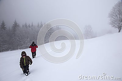 Hikers go up on snow slope in winter. Tourists trekking in winter mountains in fog Editorial Stock Photo