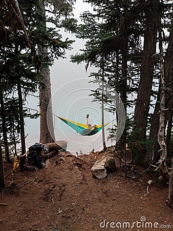 Hikers relaxing in hammock between two pine trees overlooking Joffre Lake, BC, Canada Stock Photo