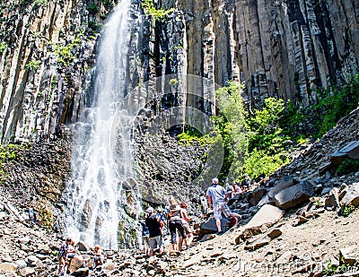 Hikers watching scenic Palisade Falls flowing over steep cliff in a lush Montana forest Editorial Stock Photo