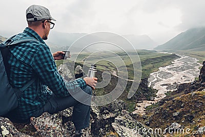 Hiking Adventure Tourism Vacation Holiday Concept. Young Traveler Holding Thermos In His Hand And Enjoy View Valley, Rear View Stock Photo