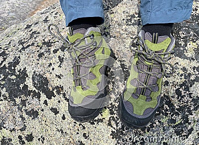 Hiking Boots closeup on the rocky mountain with green forest and lake on the background Stock Photo