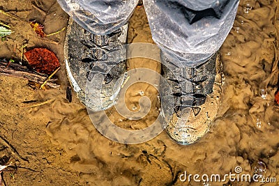 Hiking boots stuck in mud. Travel shoes covered in dirt Stock Photo