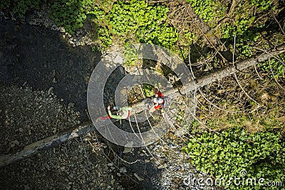 Hiking Couple Crossing River Walking Along Fallen Tree Aerial View Stock Photo