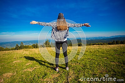 Hiking girl on top of hill with hands up enjoy mountain view Stock Photo