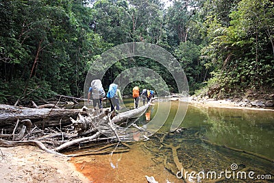 Hiking group of man crossing the river Stock Photo