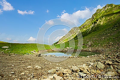 Hiking lake on the top of a mountain with blue water among green meadows Stock Photo