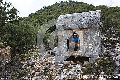Hiking Lycian way. Tourist posing for photo inside Lycian rock tomb, stretch between Myra - Alakilise Ruins, Trekking in Turkey Stock Photo