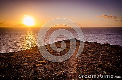 Hiking path on a rock overlooking the atlantic ocean during a colorful sunrise on the island of Gran Canaria, Canary Islands Stock Photo