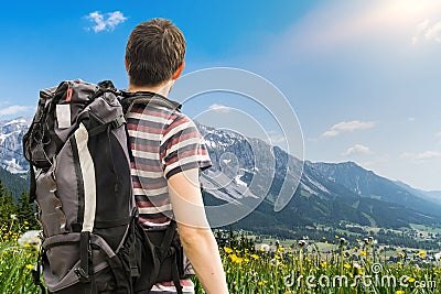 Hiking tourist with backpack from behind. Alps in background. Stock Photo