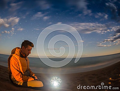 Hiking tourist have a rest in his camp at night near campfire Stock Photo