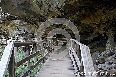 Hiking trail boardwalk under rocky overhang Stock Photo