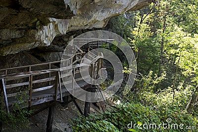Hiking trail boardwalk under rocky overhang Stock Photo