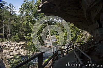 Hiking trail boardwalk under rocky overhang Stock Photo