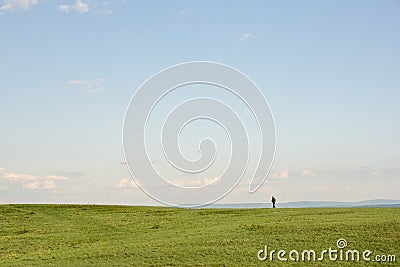 Hiking. An unknown young man walks on a green mountain on a clear summer day Stock Photo