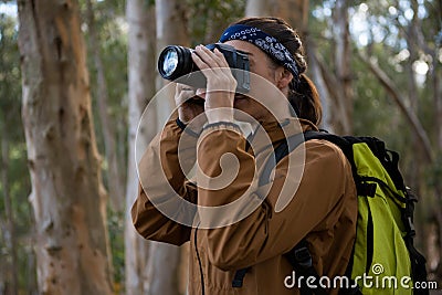 Hiker woman clicking a photo in forest Stock Photo