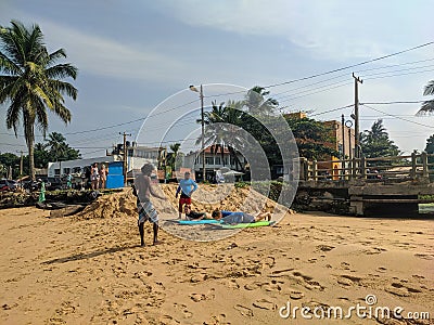 Hikkaduwa, Sri Lanka - March 4, 2022: Instructor teaches a woman and a man lying on the boards how to surf on the beach of Editorial Stock Photo