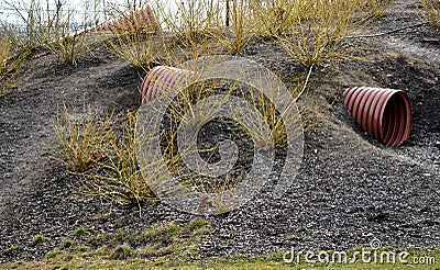 A hill with buried pipes used as a sewer. children crawl through the pipe on the playground. emergency cover, firing position on t Stock Photo