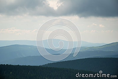 Hills and valleys under cloudy sky Stock Photo