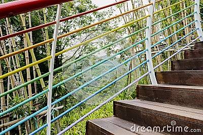 Hillside planked stairway with colorful steel handrail Stock Photo