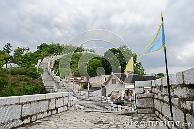 Hillside stone wall on fringe of ancient town in cloudy spring a Stock Photo