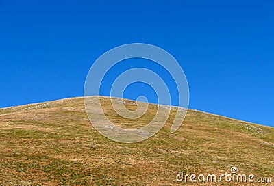 Hilltop grass meadow and bright blue hot summer sky, for background. Stock Photo