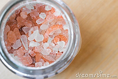 Himalayan pink rock salt in a bottle container on a wooden surface. Stock Photo