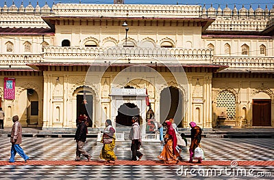 Hindu people rush past the entrance of the yellow wall temple Editorial Stock Photo