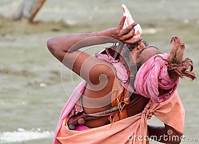 Hindu sadhu (saint) blowing conch. Editorial Stock Photo