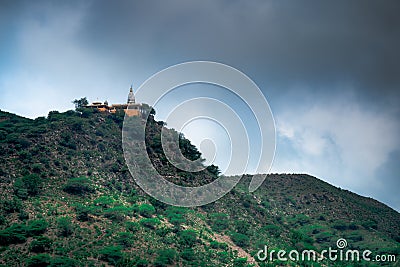 Hindu temple on a hill covered in vegetation with the tower and spire clearly visible in the distance with a background Stock Photo