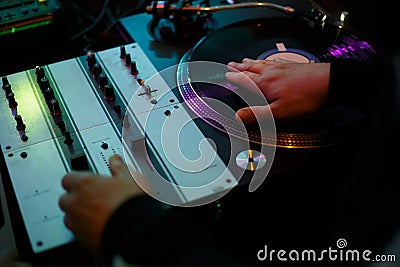 Hip hop dj scratching vinyl record with music on party in night club. Professional disc jockey scratches records on turntables in Stock Photo