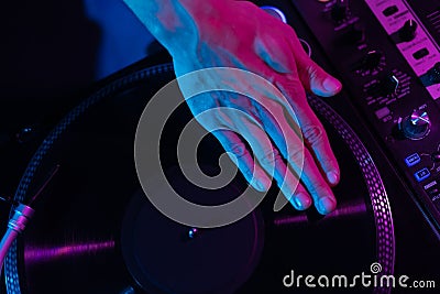 Hip hop DJ scratching vinyl record on turntable. Club disc jockey mixing records on party, focus on hand Stock Photo