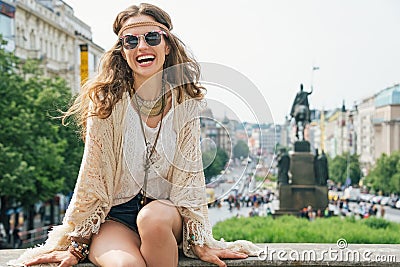 Hippy-looking woman tourist sitting on stone parapet in Prague Stock Photo
