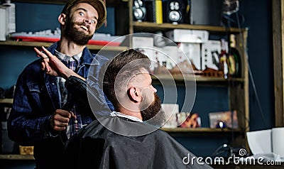 Hipster bearded client getting hairstyle. Barber on cheerful face with hairdryer styling hair of client. Barber with Stock Photo