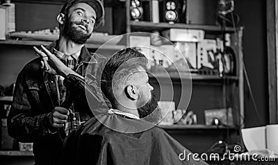 Hipster bearded client getting hairstyle. Barber on cheerful face with hairdryer styling hair of client. Barber with Stock Photo