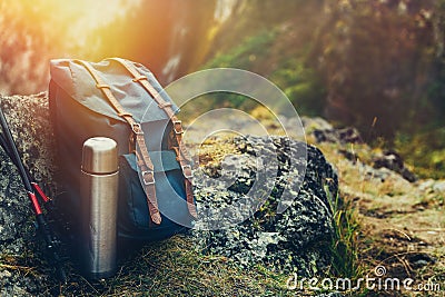 Hipster Blue Backpack, Thermos And Trekking Poles Closeup, Front View. Tourist Traveler Bag On Rocks Background. Adventure Hiking Stock Photo