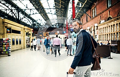 Hipster businessman with suitcase walking inside subway station in London. Stock Photo
