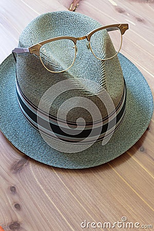 Hipster concept, fedora hat with horn rimmed vintage glasses perched on top, neutral wood background Stock Photo