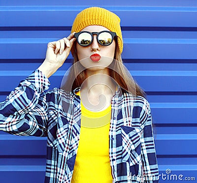 Hipster cool girl in sunglasses and colorful clothes having fun over blue Stock Photo