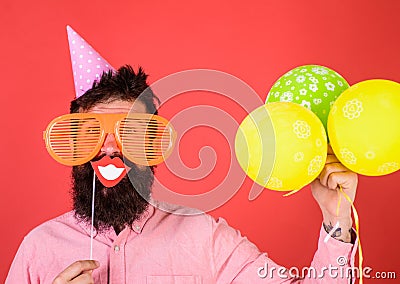 Hipster in giant sunglasses celebrating. Guy in party hat with air balloons celebrates. Photo booth fun concept. Man Stock Photo