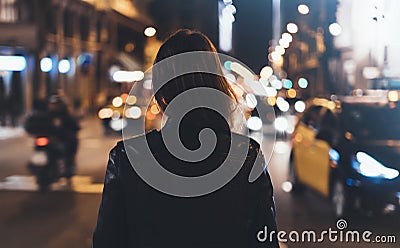 Hipster girl in black leather jacket from back on background illumination glow bokeh light in night atmospheric christmas city, hi Stock Photo