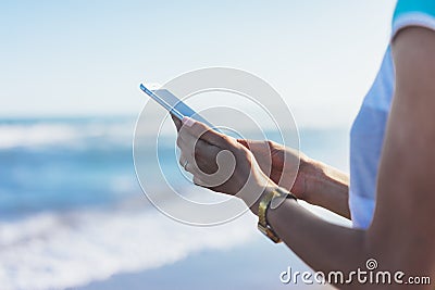 Hipster girl photograph on smart phone gadget in sand coastline, mock up of blank screen. Traveler hold and using in female hand Stock Photo