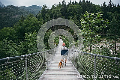 Hipster hiker man and dog on suspension bridge Stock Photo